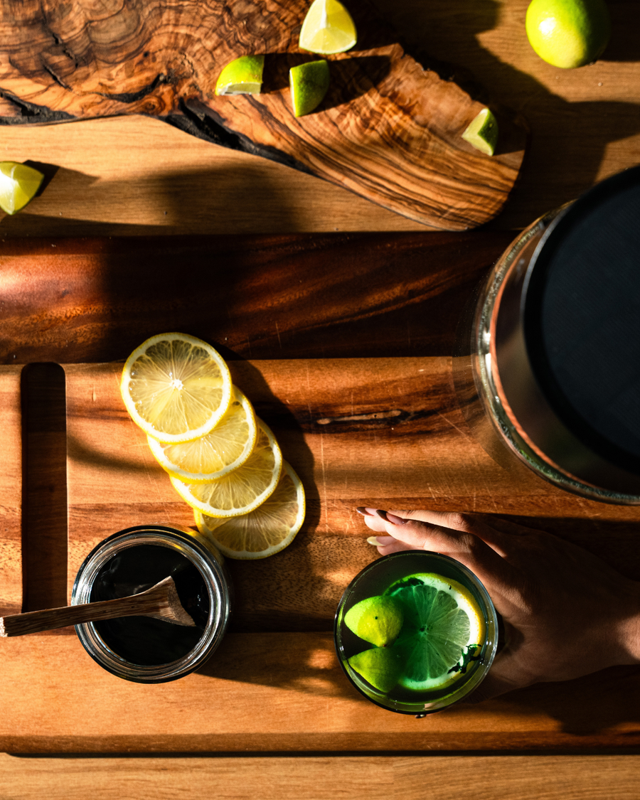 Frische Spirulina im Glas mit Zitrone auf einem Holzbrett