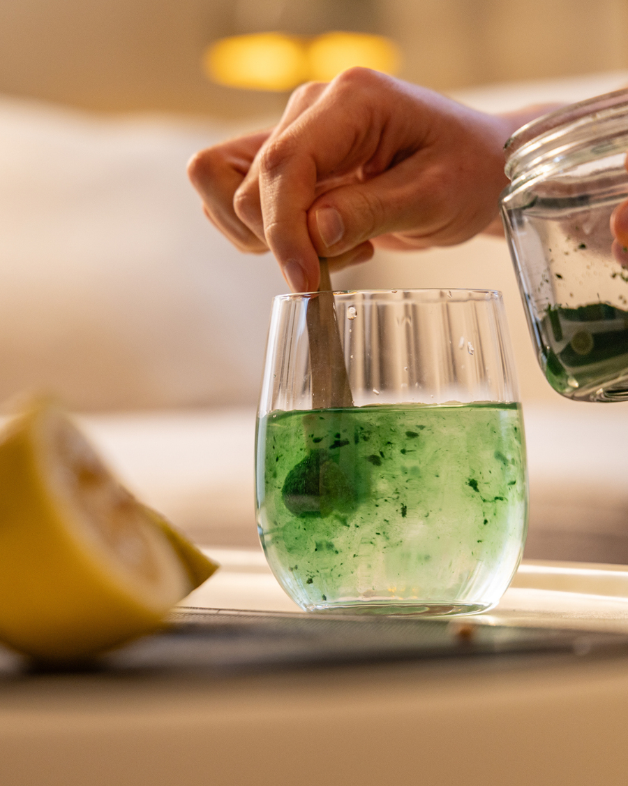 Frische Spirulina wird in ein Glas Wasser gerührt