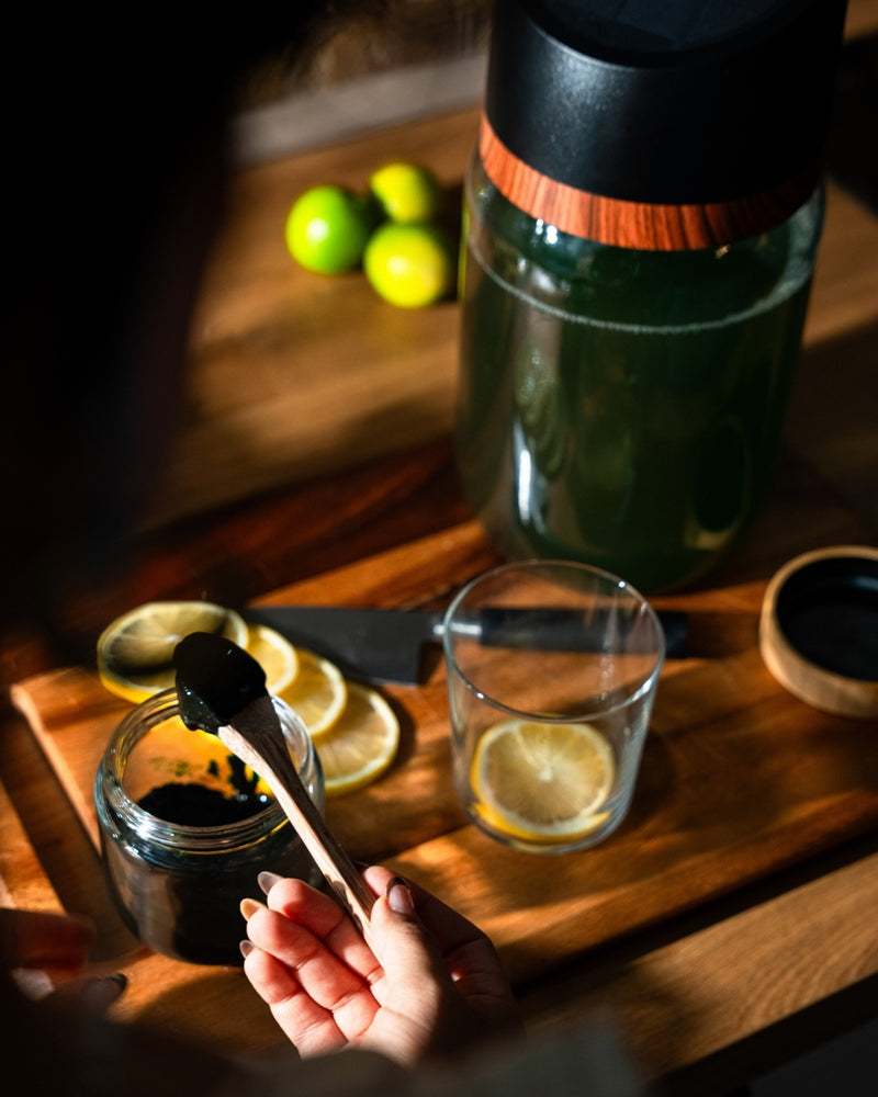 Frische Spirulina wird zu einem Glas Wasser mit Zitrone gegeben